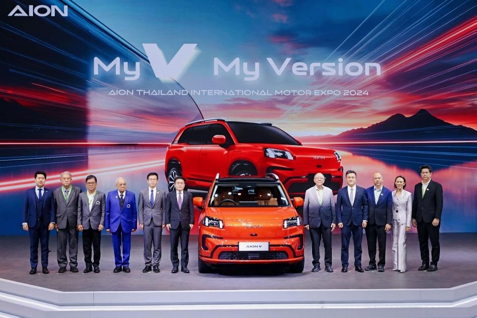A group of men standing in front of a red carDescription automatically generated